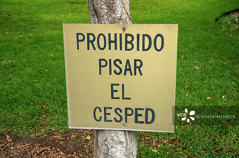 公园树干上禁止踩踏草坪的西班牙语标志图片素材