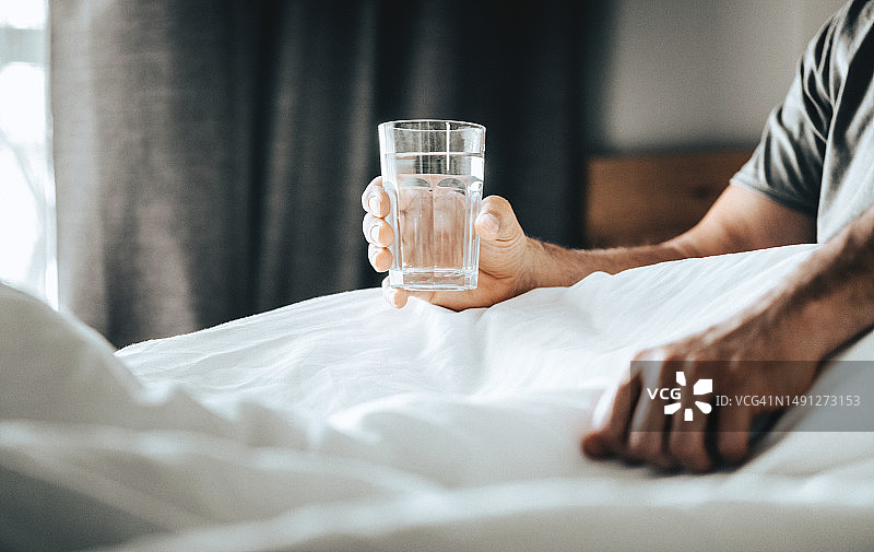 起床后早晨饮用水，手持玻璃杯特写，健康生活方式概念图片素材