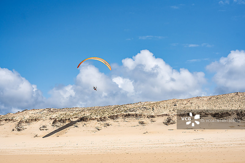 男人在法国沙滩的沙丘上玩滑翔伞图片素材
