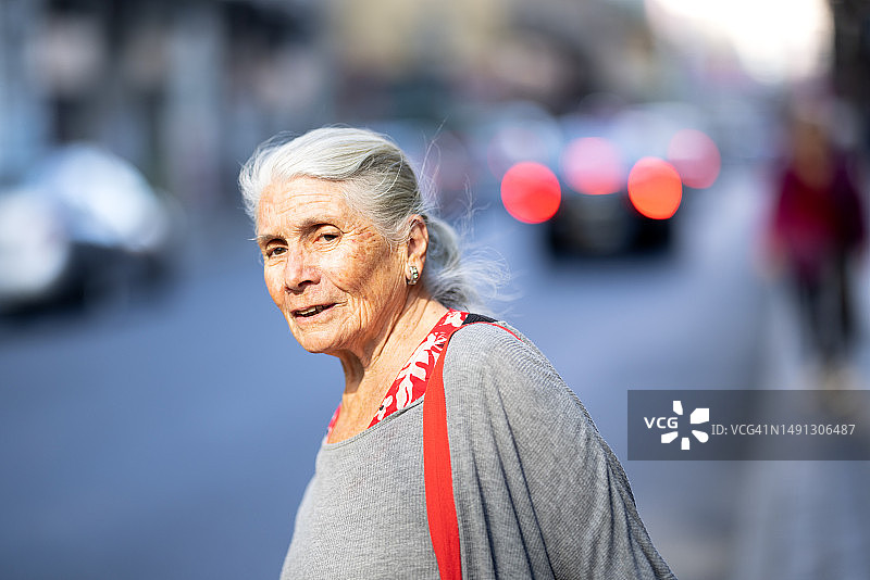 在智利瓦尔帕莱索市，老年妇女站在人行道上寻找出租车图片素材