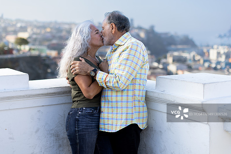 在瓦尔帕莱索屋顶深情拥吻的上镜中年夫妇图片素材