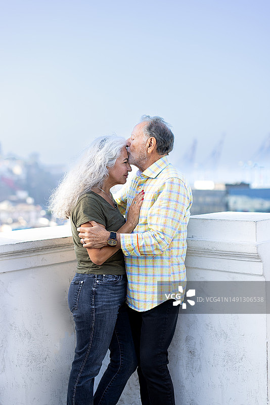 竖版照片：年长夫妇亲密相拥，丈夫亲吻妻子的额头图片素材