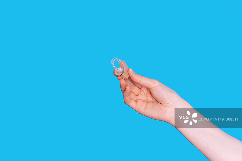蓝色背景下手持助听器图片素材
