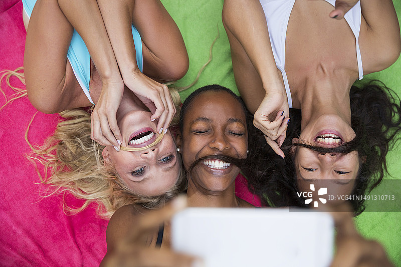 快乐的朋友模仿胡须躺在彩色毯子上图片素材