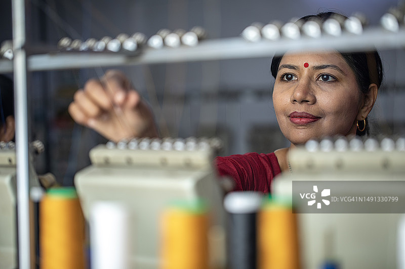 女工在纺织设备上拿着线轴图片素材