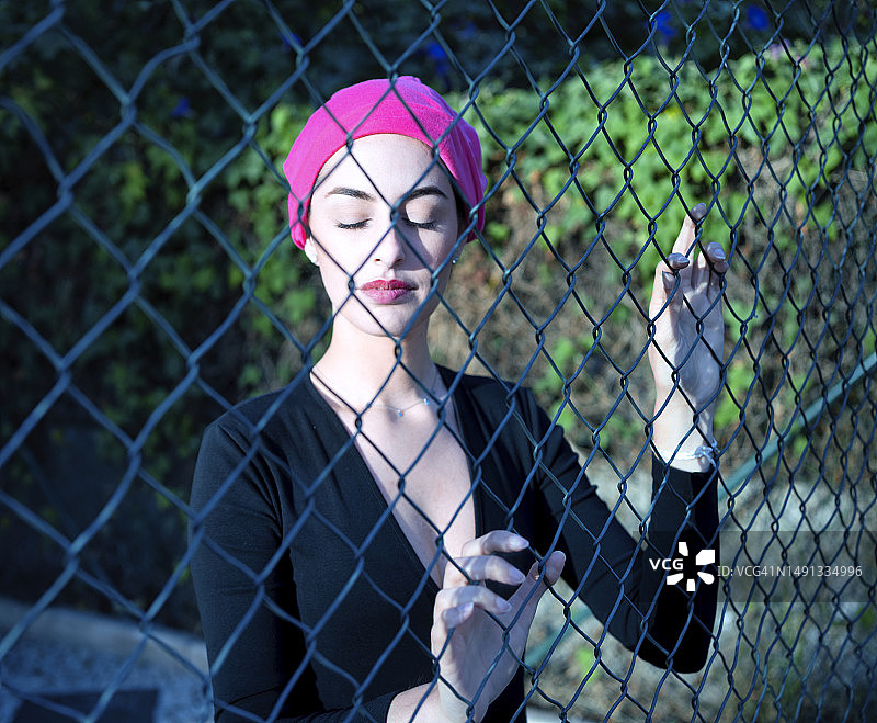 年轻的棕发女人闭着眼睛，戴着粉红色的乳腺癌支持围巾，感受着疾病带来的痛苦图片素材