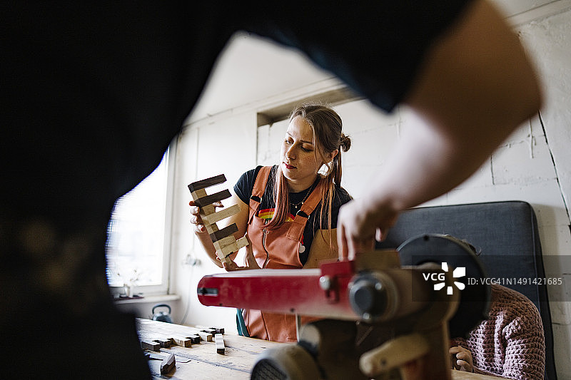 身穿工装裤的年轻女人正在光线下检查木材图片素材