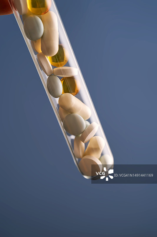 蓝色背景试管中的药丸、维生素和膳食补充剂图片素材