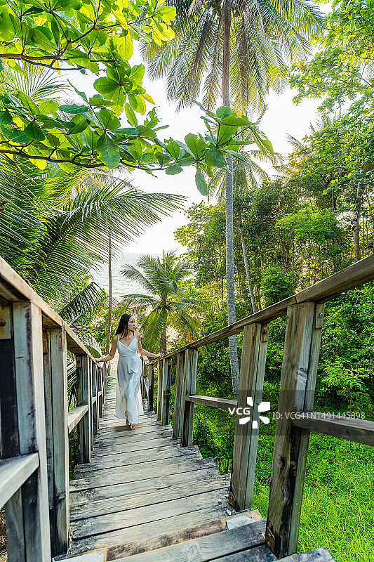 泰国普吉岛奈通海滩的木桥，椰树与森林环绕，一位女士走在桥上图片素材