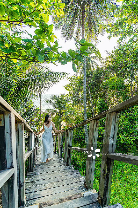 泰国普吉岛奈通海滩的木桥，椰树与森林环绕，一位女士走在桥上图片素材