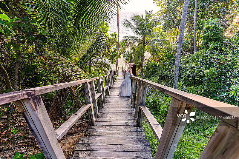 泰国普吉岛奈通海滩的木桥，椰树与森林环绕，一位女士走在桥上图片素材