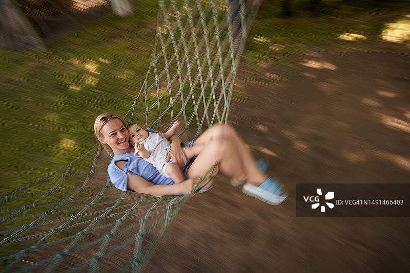 快乐的母亲和女婴在后院摇摆的模糊运动的俯视图图片素材