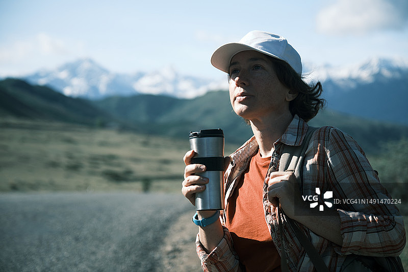 女人在路边车旁用旅行杯喝水图片素材