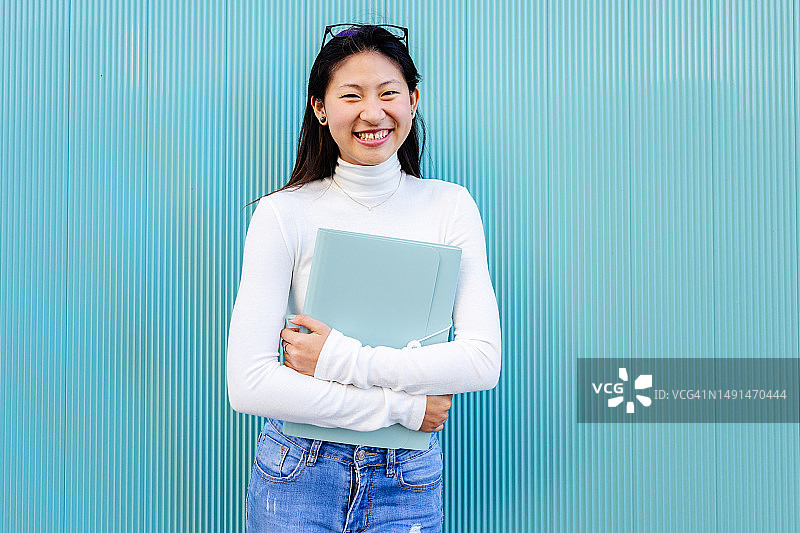 蓝色背景下的快乐亚洲女学生肖像图片素材