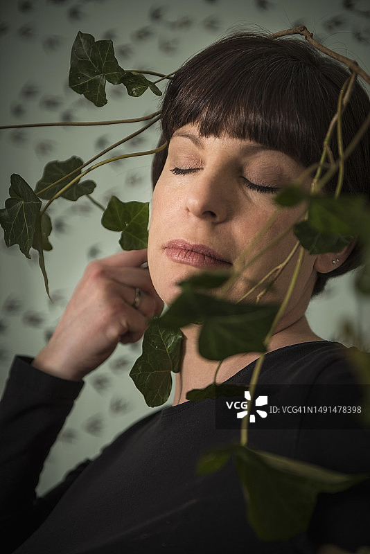 被绿色常春藤叶包裹的中年妇女图片素材