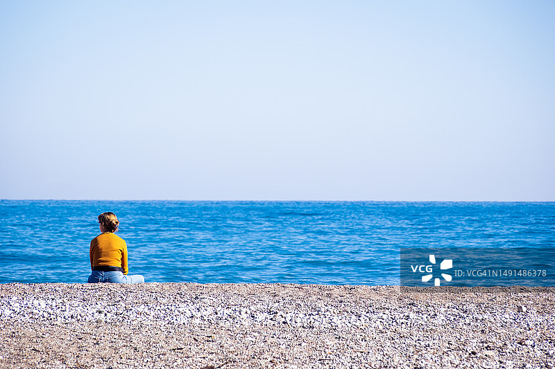 坐在地中海海滩上的年轻女人图片素材