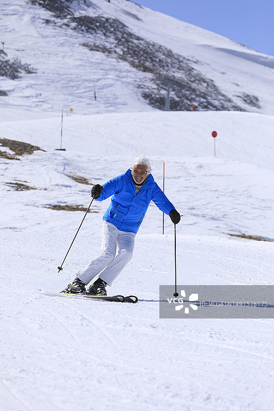 在阳光明媚的滑雪胜地上享受滑雪的灰发老人图片素材