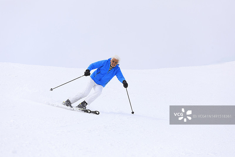充满活力的灰发老人享受滑雪乐趣图片素材