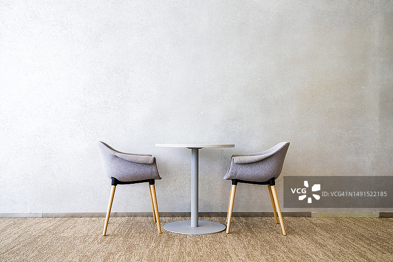 白色墙壁和水泥地面的现代室内，带桌子的两把木椅图片素材