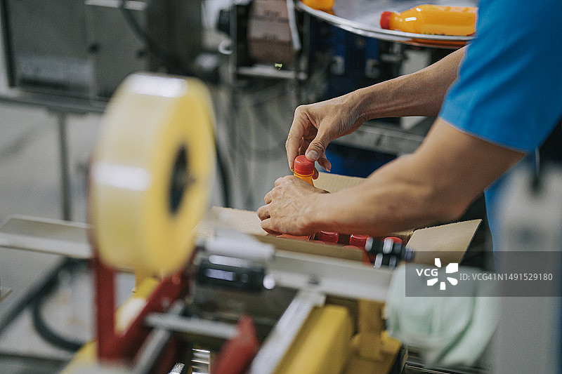 包装前，检查橙汁瓶的中国生产线工人图片素材