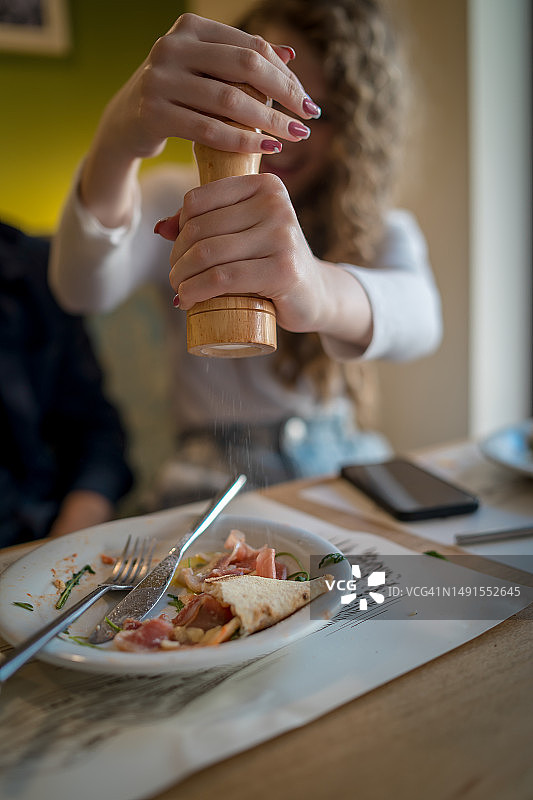 在餐桌旁使用胡椒研磨器的女人图片素材