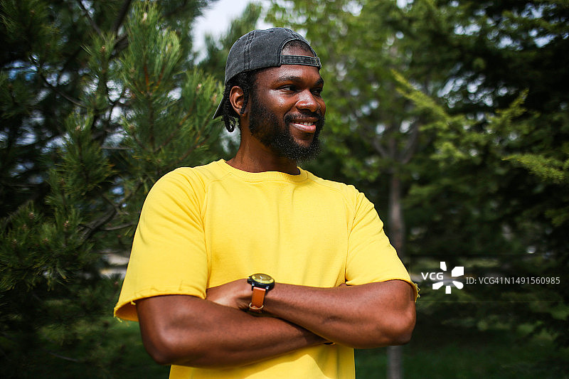 绿色背景下戴帽子、穿黄色衬衫、双手被绑的年轻黑人男性肖像图片素材