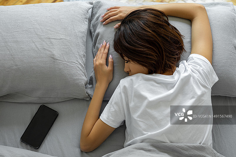 在床上玩手机的熟睡女人图片素材