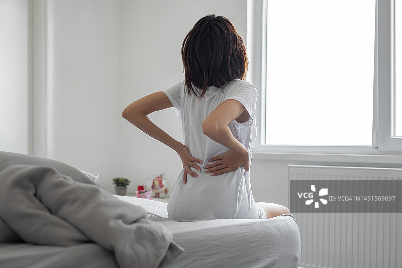 女人因背痛按摩酸痛的肌肉图片素材
