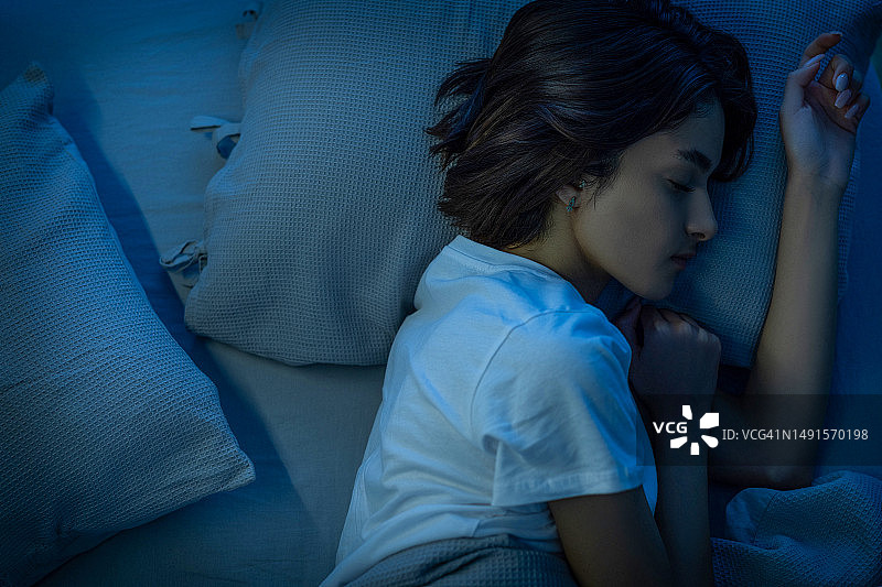 夜晚，女人在卧室的床上舒适地睡觉图片素材