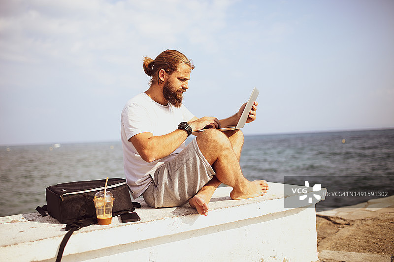 男人在沙滩上放松时用笔记本电脑阅读邮件照片图片素材