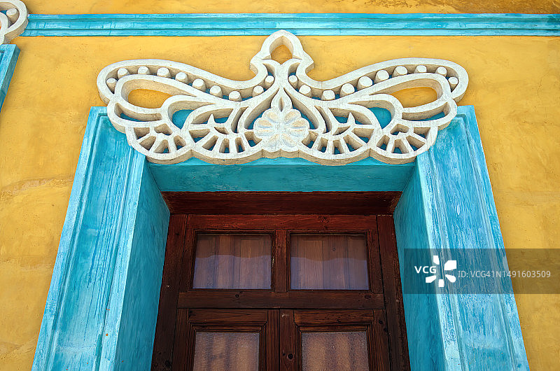 殖民时期建筑的浅蓝色窗框上方，饰有黄色粉刷墙面的华丽白色三角墙装饰图片素材