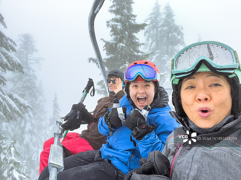 多种族家庭和朋友在下雪天乘坐缆车自拍图片素材