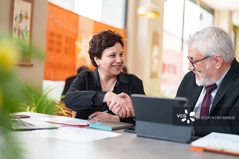 两位商务人士在餐桌上握手图片素材