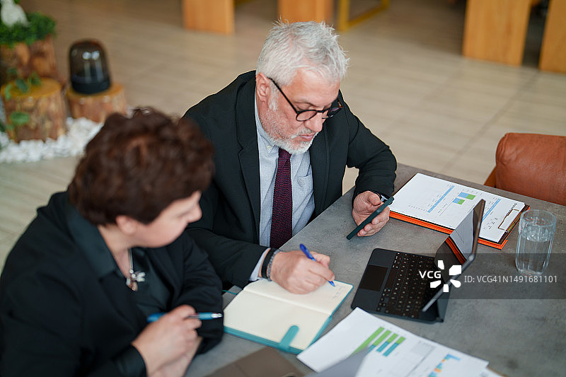 商务人士在餐厅使用便携式信息设备和文件图片素材