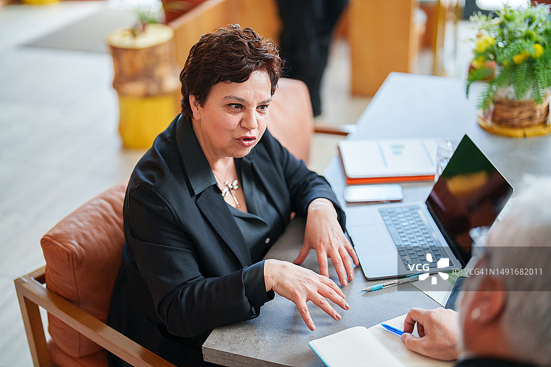 商务女强人与商务人士使用便携信息设备和文件交谈图片素材