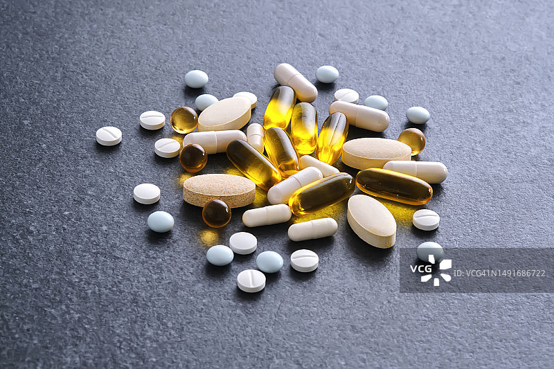 深色桌子上的药片、维生素和膳食补充剂图片素材
