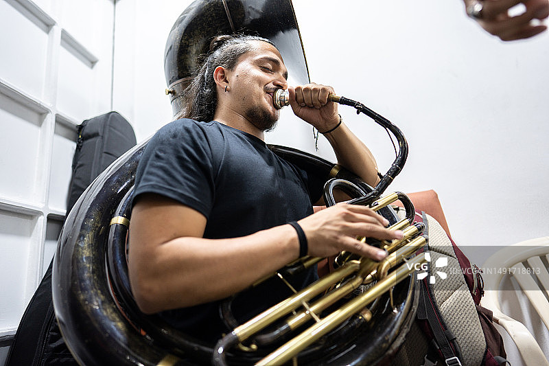 在音乐会后台闭着眼睛演奏低音号的男音乐人图片素材