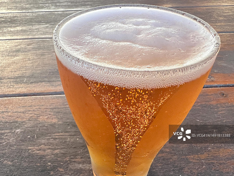 木桌上装满泡沫的冰镇啤酒杯图片素材