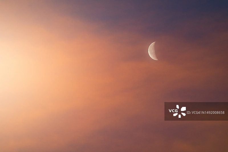 夜间美景：半月在橙色暮云中显露环形山图片素材