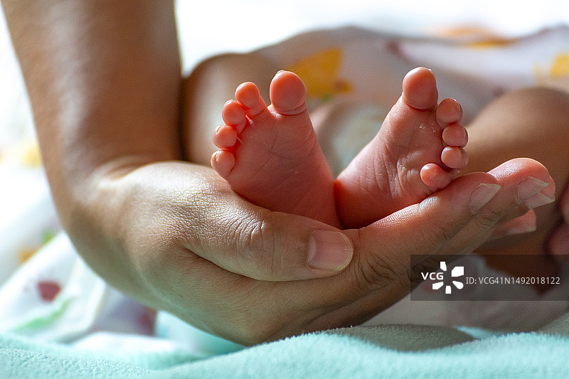 父母用手托着新生婴儿的脚图片素材