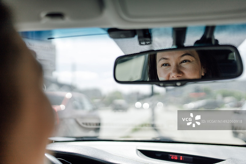 汽车挡风玻璃和后视镜中快乐女士注视道路的倒影图片素材