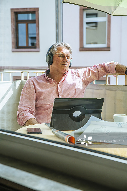 中年男人戴耳机使用平板电脑图片素材