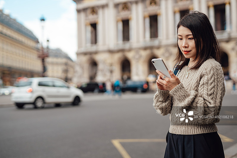 在巴黎街头使用智能手机的年轻亚洲女商人图片素材