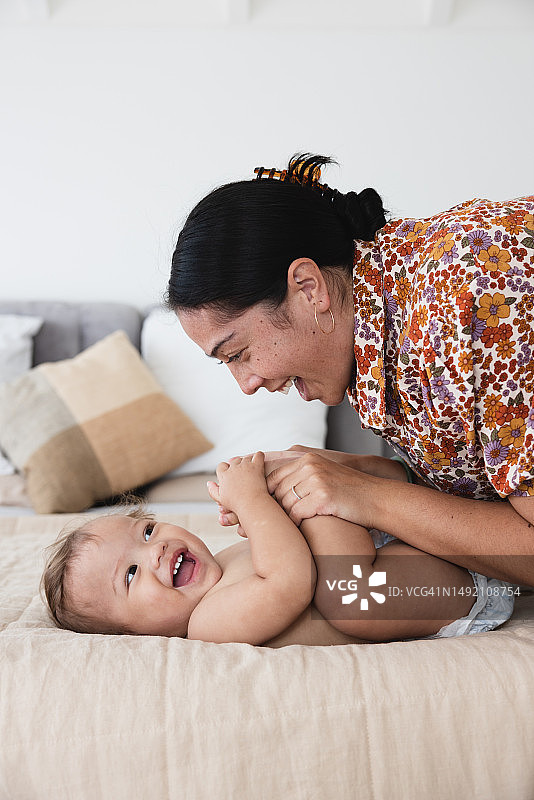在床上和孩子玩耍的快乐女人图片素材