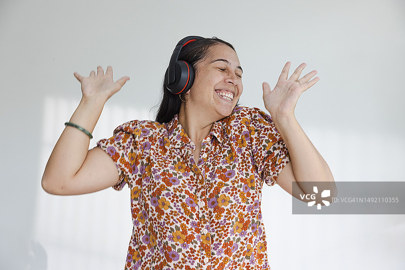 闭着眼睛，笑着挥手的戴耳机女人图片素材