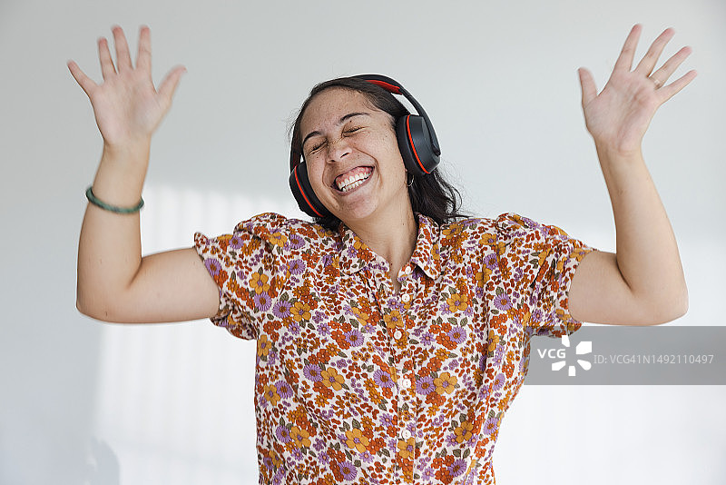 闭着眼睛，笑着挥手的戴耳机女人图片素材