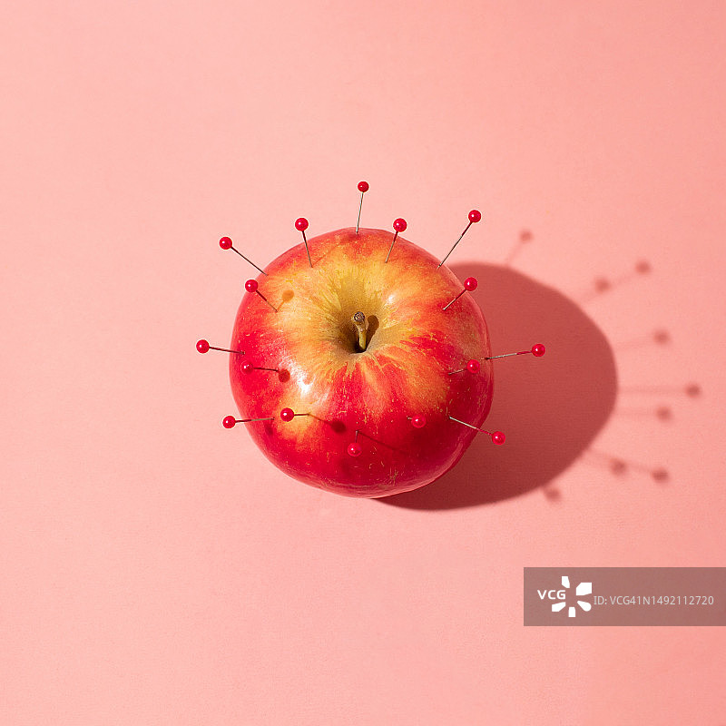 浅橙色背景上的带针红苹果，简约风格，食物概念图片素材