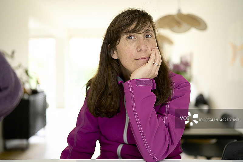 女人在餐桌旁休息，微笑看着镜头的肖像图片素材