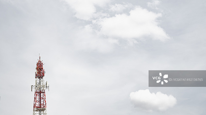 红白相间的通信塔，位于云层背景的中心图片素材