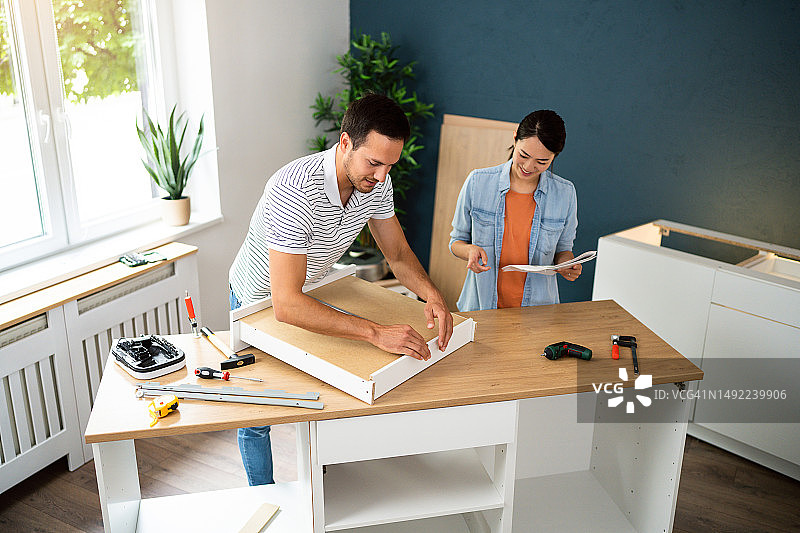 情侣在他们的新公寓里一起组装家具图片素材